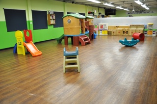 The infant and toddler room, with a soft-play climbing structure and slide on an open wood floor